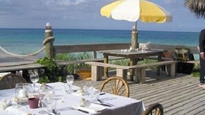 Een houten terras met een eettafel, met uitzicht op de oceaan.