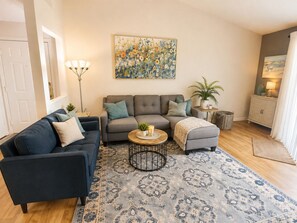 A living room with a grey sofa, a blue armchair, a round coffee table, and a patterned rug.