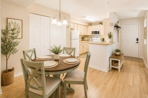 A dining area with a round table, chairs, and a chandelier.