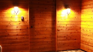 Ein Zimmer mit Holzvertäfelung, zwei Wandleuchten und einem sichtbaren Türgriff.