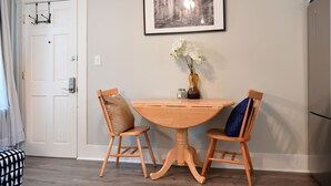 Ein Essbereich mit einem runden Holztisch, zwei Stühlen, einer Blumenvase und einem gerahmten Bild an der Wand.