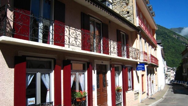 A row of traditional buildings with balconies, red shutters, and flower boxes. - RENT CHARMING STUDIO (Cauterets)