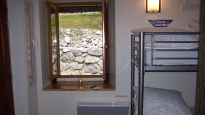 A bunk bed room with a stone wall view, a window, and a sign reading "Totem". - RENT CHARMING STUDIO (Cauterets)