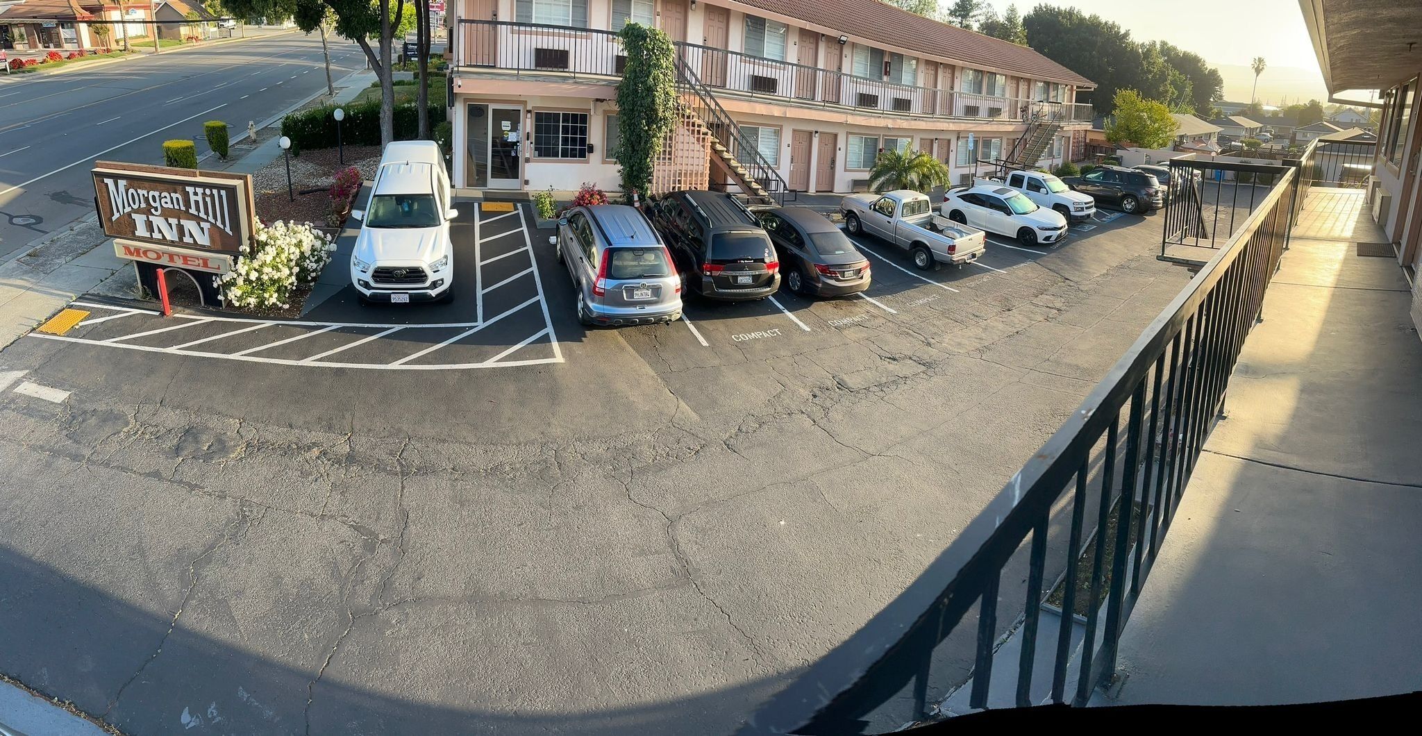 Un estacionamiento con varios coches, un cartel de Morgan Hill Inn Motel y un edificio con múltiples balcones y una escalera.