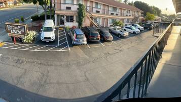 Un estacionamiento con varios coches, un cartel de Morgan Hill Inn Motel y un edificio con múltiples balcones y una escalera.