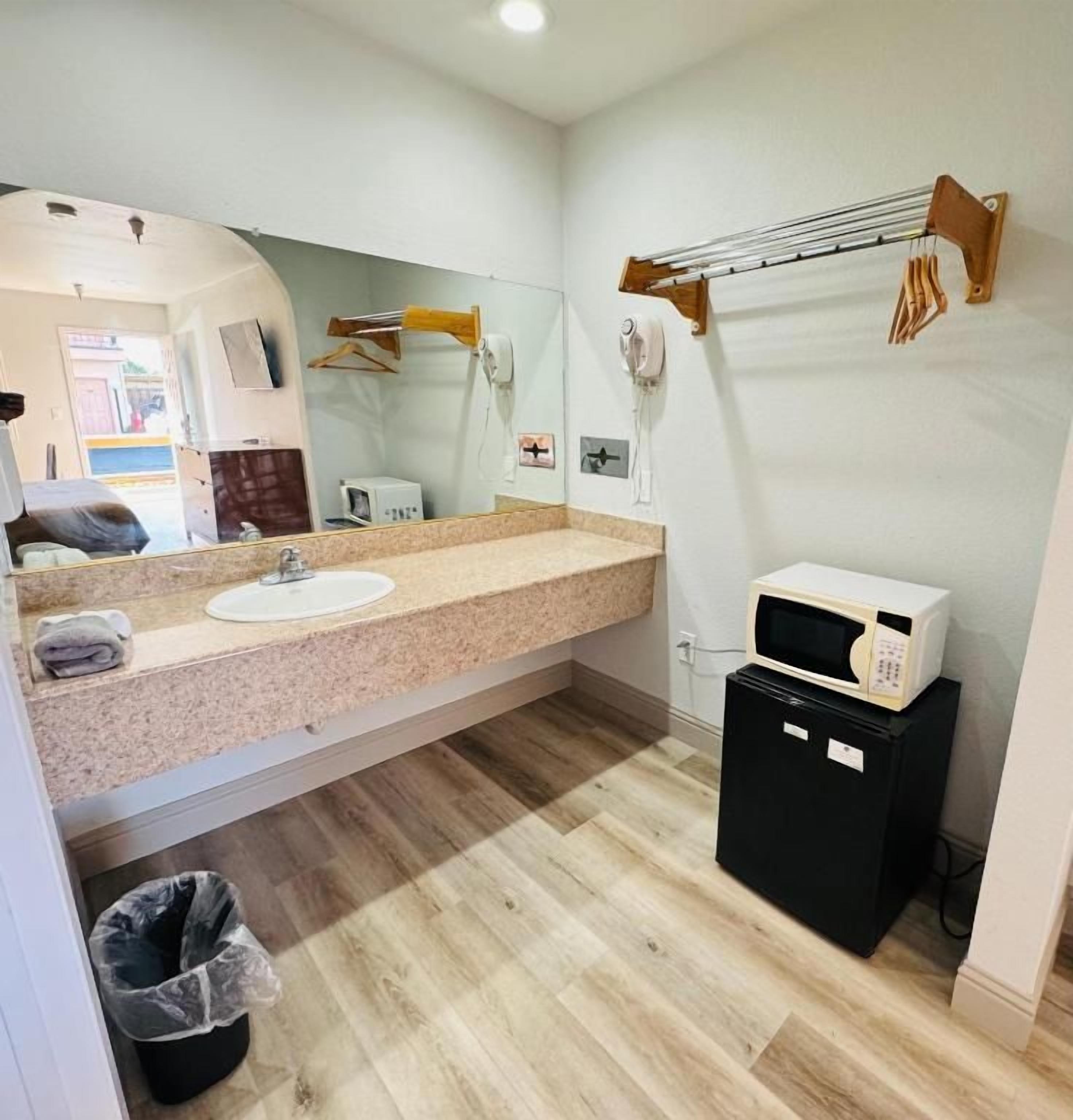 A bathroom with a sink, mirror, towel rack, and a microwave on a small cabinet.