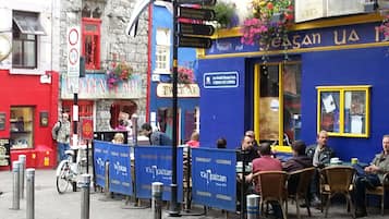 A street scene with a blue building, a signpost with directions, and people sitting outside.