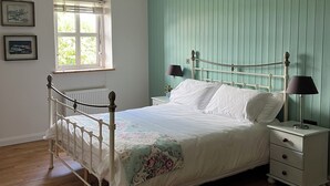 A bedroom with a bed, bedside tables, a window, and a ceiling fan. - Connemara Stone Barn on Wild Atlantic Way, walk to beach, near Aran Island Ferry (Inverin)