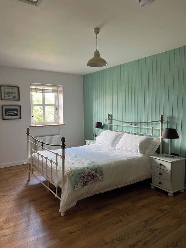 A bedroom with a bed, bedside tables, a window, and a ceiling fan. - Connemara Stone Barn on Wild Atlantic Way, walk to beach, near Aran Island Ferry (Inverin)