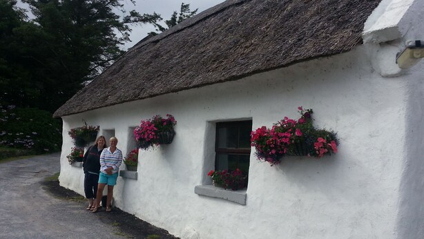 A white building with a thatched roof, windows with flower boxes, and a gravel path leading to it. - Connemara Stone Barn on Wild Atlantic Way, walk to beach, near Aran Island Ferry (Inverin)