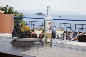 A table with a bottle of white wine, two glasses, and a plate of grapes and watermelon.