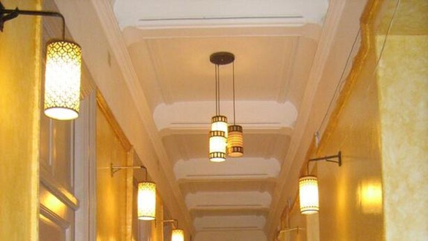 Un couloir bordé de part et d’autre par une série de portes, chacune donnant accès à une pièce individuelle.