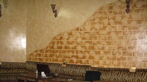 Une pièce avec un canapé à rayures zébrées, une petite table en bois et un mur décoré d’un motif en briques.