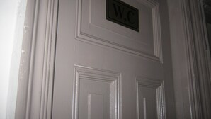 Une porte blanche avec une pancarte au-dessus indiquant « W.C. ».