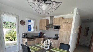 Una cocina moderna con comedor, que incluye un mantel a rayas, sillas negras y una lámpara colgante original.