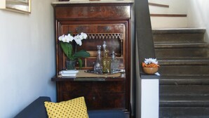 A living room with a dark blue sofa, yellow pillows, a wooden cabinet with decorative items, and a staircase. - Breathtaking view, terrace and elevator (Firenze)