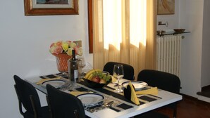 A dining table set with plates, cutlery, a bowl of fruit, and a vase of flowers. - Breathtaking view, terrace and elevator (Firenze)