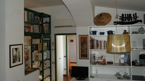 A room with a bookshelf, a television, and a decorative lamp. - Breathtaking view, terrace and elevator (Firenze)