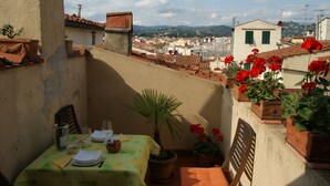 A balcony with a table set for two, potted plants, and a view of a cityscape. - Breathtaking view, terrace and elevator (Firenze)