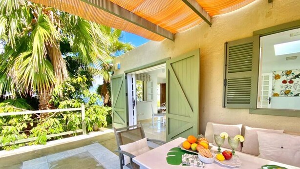 An outdoor dining area with a table set for two, surrounded by greenery and a covered seating area. - Private villa with pool with amazing views . (La Guancha)