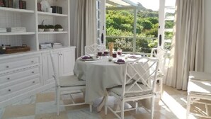 A dining area with a table set for four, surrounded by white chairs, with a view of greenery outside. - Private villa with pool with amazing views . (La Guancha)
