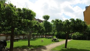 A courtyard with picnic tables, a gravel path, and trees.