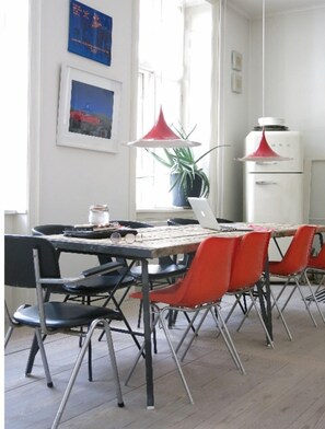 A room with a table, chairs, a laptop, a potted plant, and a water heater.