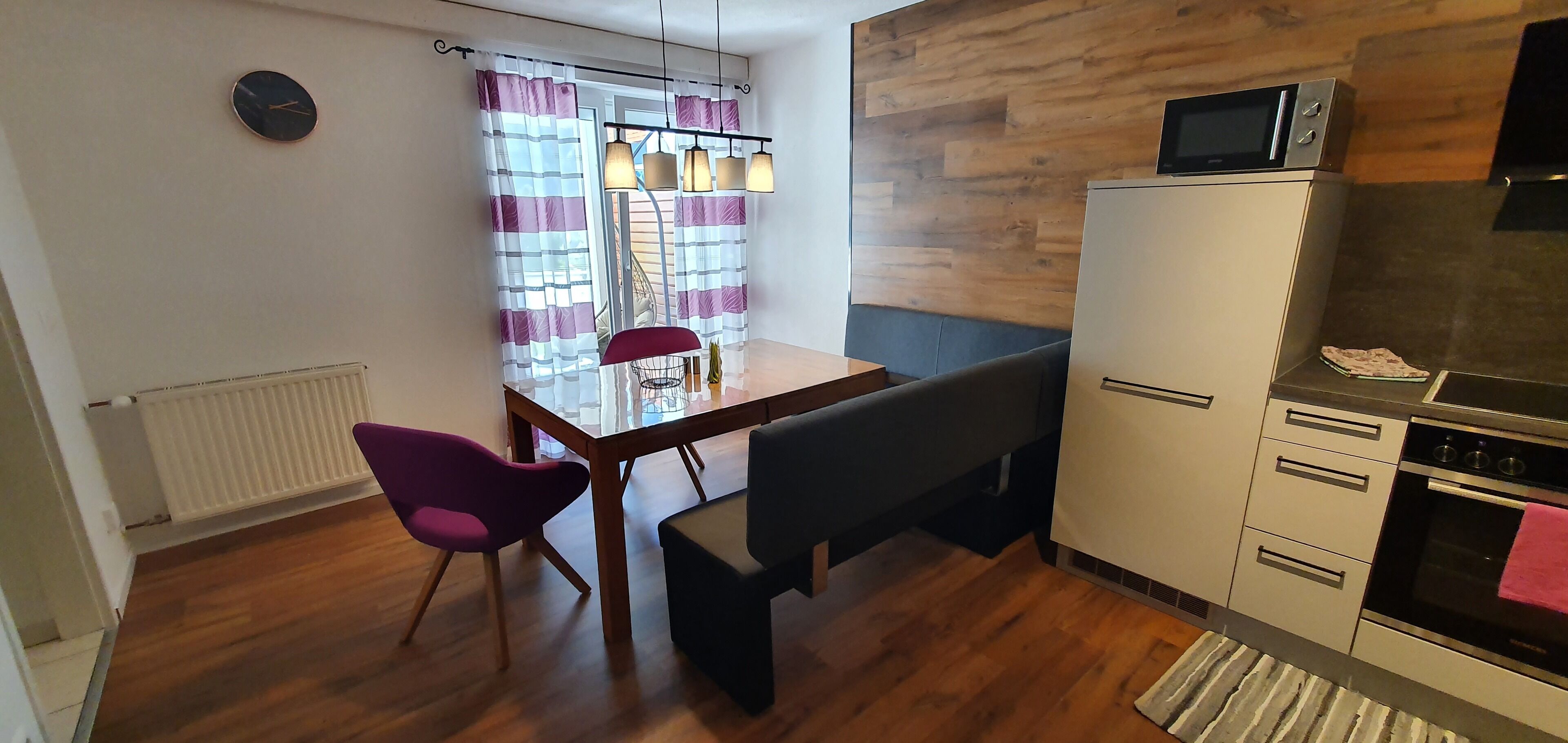 Une cuisine compacte équipée d’un four à micro-ondes, d’un four traditionnel et d’un coin repas avec une table et des chaises.