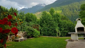 A garden with a stone bench, a wooden table, and a stone oven. - Large 105m² apartment with terrace for 4 to 6 persons & beautiful south view! (Flattach)