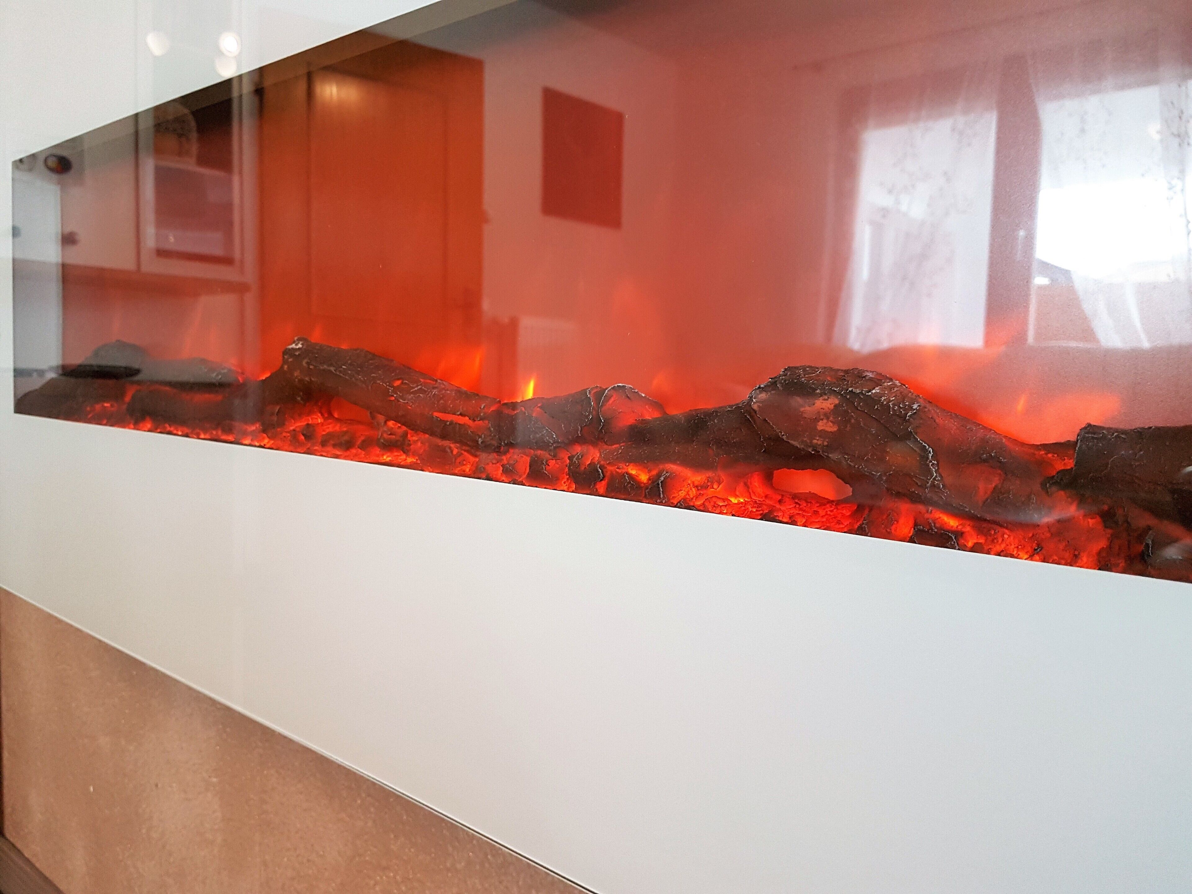 A glass enclosure with a fire feature, including logs and glowing embers.