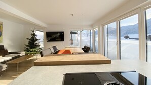 Una sala de estar moderna con un ventanal grande, una chimenea y un comedor con vistas a un paisaje nevado.
