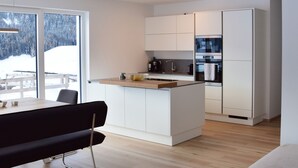 Una cocina moderna con armarios blancos, una isla central y un comedor con un banco negro.