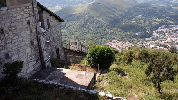 Ein Steinhaus mit Blick auf ein Tal und Berge.