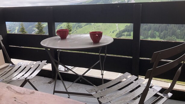 A balcony with a table and two red cups, overlooking a mountainous landscape. - SKIS ON FOOTS-WIFI- GARAGE (optional) -NICE VIEW-2 ROOMS (Les Allues)