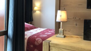 A room with a bed, a lamp, and a wooden wall. - SKIS ON FOOTS-WIFI- GARAGE (optional) -NICE VIEW-2 ROOMS (Les Allues)