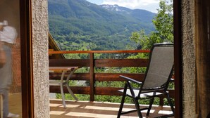 A balcony with a wooden floor, a chair, and a table. -    Comfortable apartment in chalet with splendid view   (Allos)