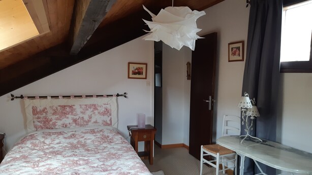 Ein Schlafzimmer mit Bett, Schreibtisch, Stuhl, Lampe und Tür.