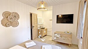Een slaapkamer met een bed, nachtkastje, kaptafel, spiegel en een tv aan de muur.