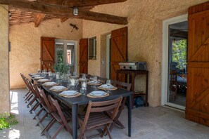 A dining area with a long table set for a meal, wooden chairs, and a grill station.