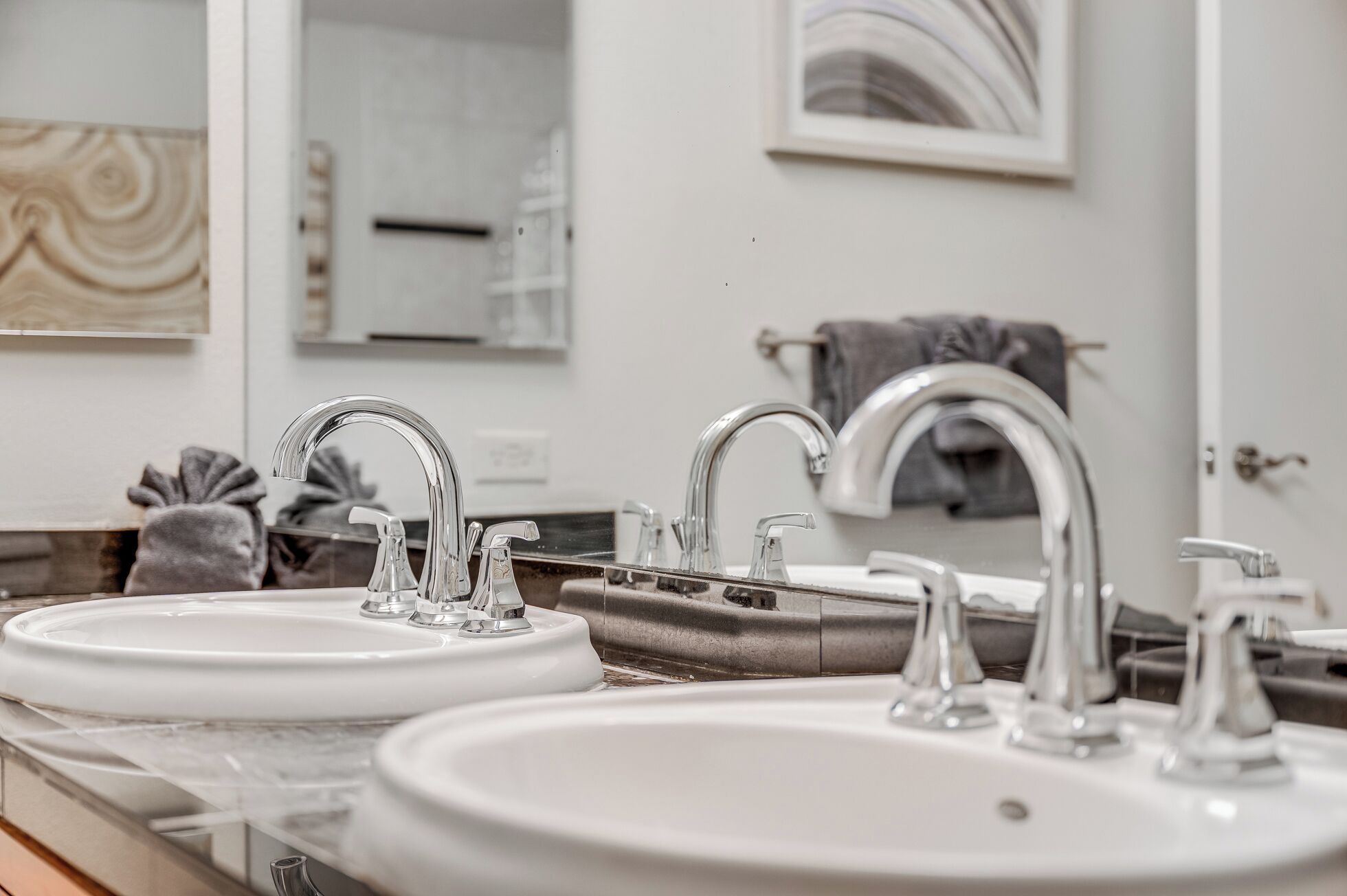 A bathroom with two sinks, a mirror, and a towel rack.