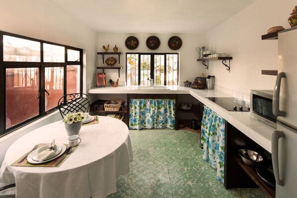 Una cocina compacta con una mesa de comedor para dos personas, una ventana con vistas y un refrigerador.