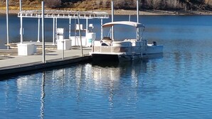 Une jetée avec un bateau, un espace de repos abrité et un lac paisible.