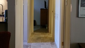 Un couloir étroit doté d’un sol recouvert de moquette, d’une armoire en bois et d’un tableau encadré accroché au mur.