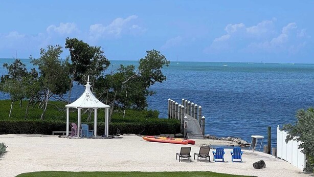 Ein Strand mit einer Laube, Liegestühlen und Kajaks.
