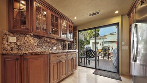 A kitchen with wooden cabinets, a granite countertop, and a stainless steel refrigerator. - Luxury Lake Front PGA West Golf Course View Townhome / Private Spa / Adults Only (La Quinta)