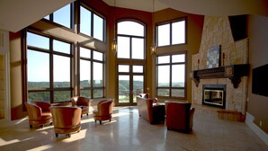 A spacious living room with large windows, a fireplace, and leather armchairs.