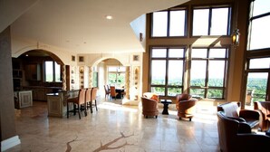 A spacious living area with a large window, a kitchen, and a dining area.