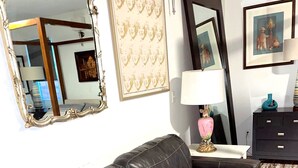 Un salon avec un canapé en cuir noir, une lampe blanche et un tableau encadré accroché au mur.