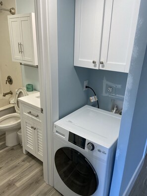 A laundry room with a front-loading washer and dryer, a toilet, and a cabinet above the sink. - # 314 DIRECT OCEANFRONT VILLA LOCATED IN NORTH FOREST BEACH AREA (Hilton Head Island)