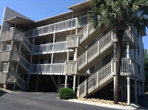 A multi-story building with balconies, a palm tree, and a parking area. - # 314 DIRECT OCEANFRONT VILLA LOCATED IN NORTH FOREST BEACH AREA (Hilton Head Island)